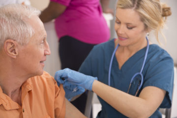 Nurse gives flu vaccine to senior adult patient at pharmacy.