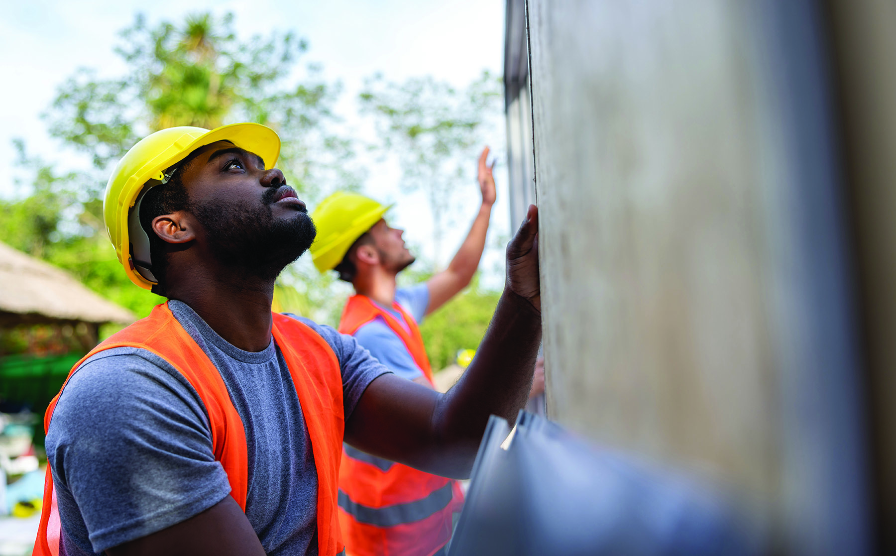 Team of construction workers installing panels while building a manufactured house - construction industry concepts