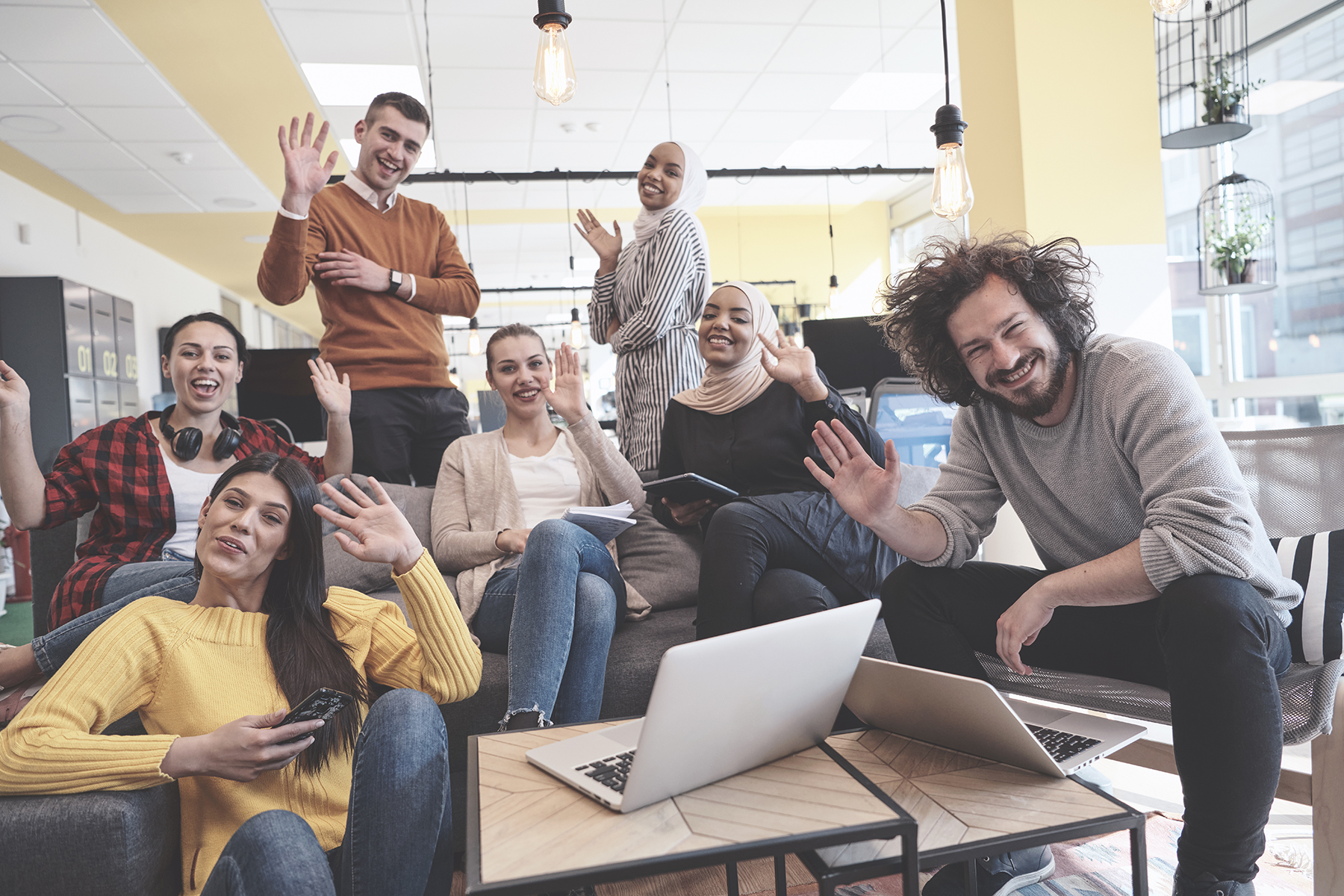 group of seven staff members celebrating while sitting and standing in open office area