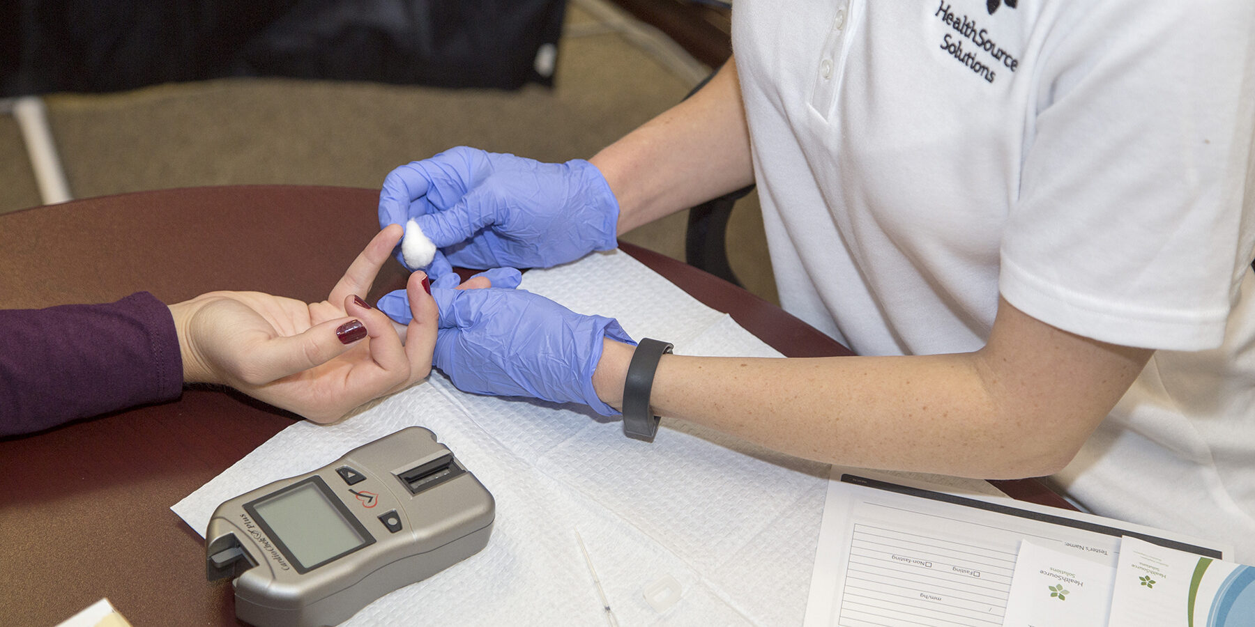 HSS.fingerstick Nurses hands taking blood from a patient for a biometric screening