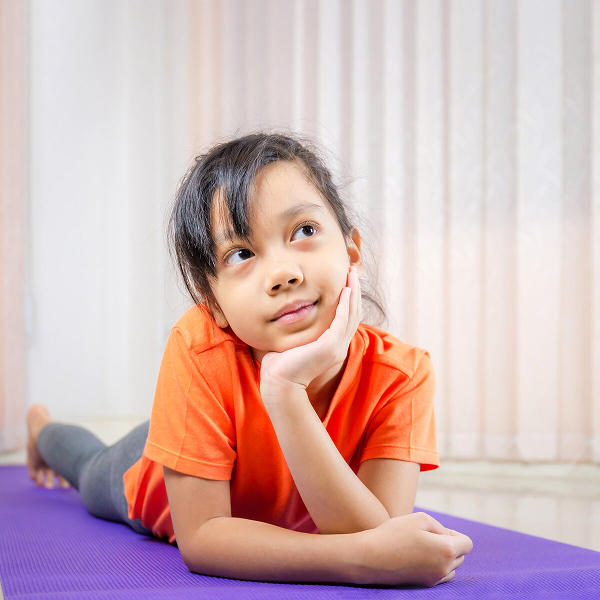 Cheerful little cute girl smiling and thinking on the yoga mats, Happiness kid concept