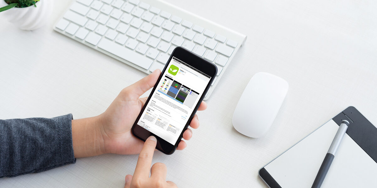 hand holding phone showing mobile app and touching on workspace table