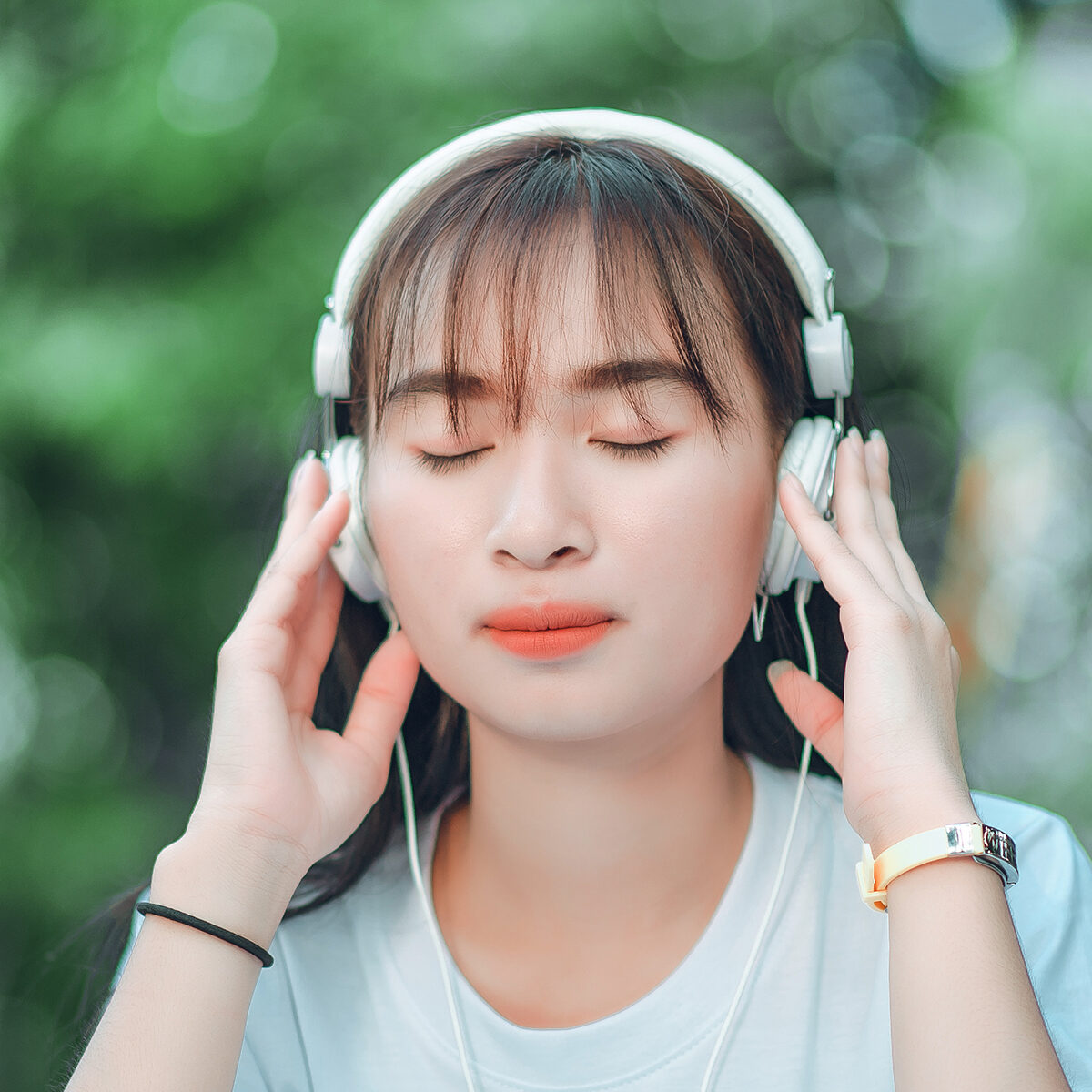Listening to music. A beautiful woman with headphones is relaxing on her desk. Close your eyes and meditate, meditate. She is listening to music using her smartphone, chill and relaxation concept.