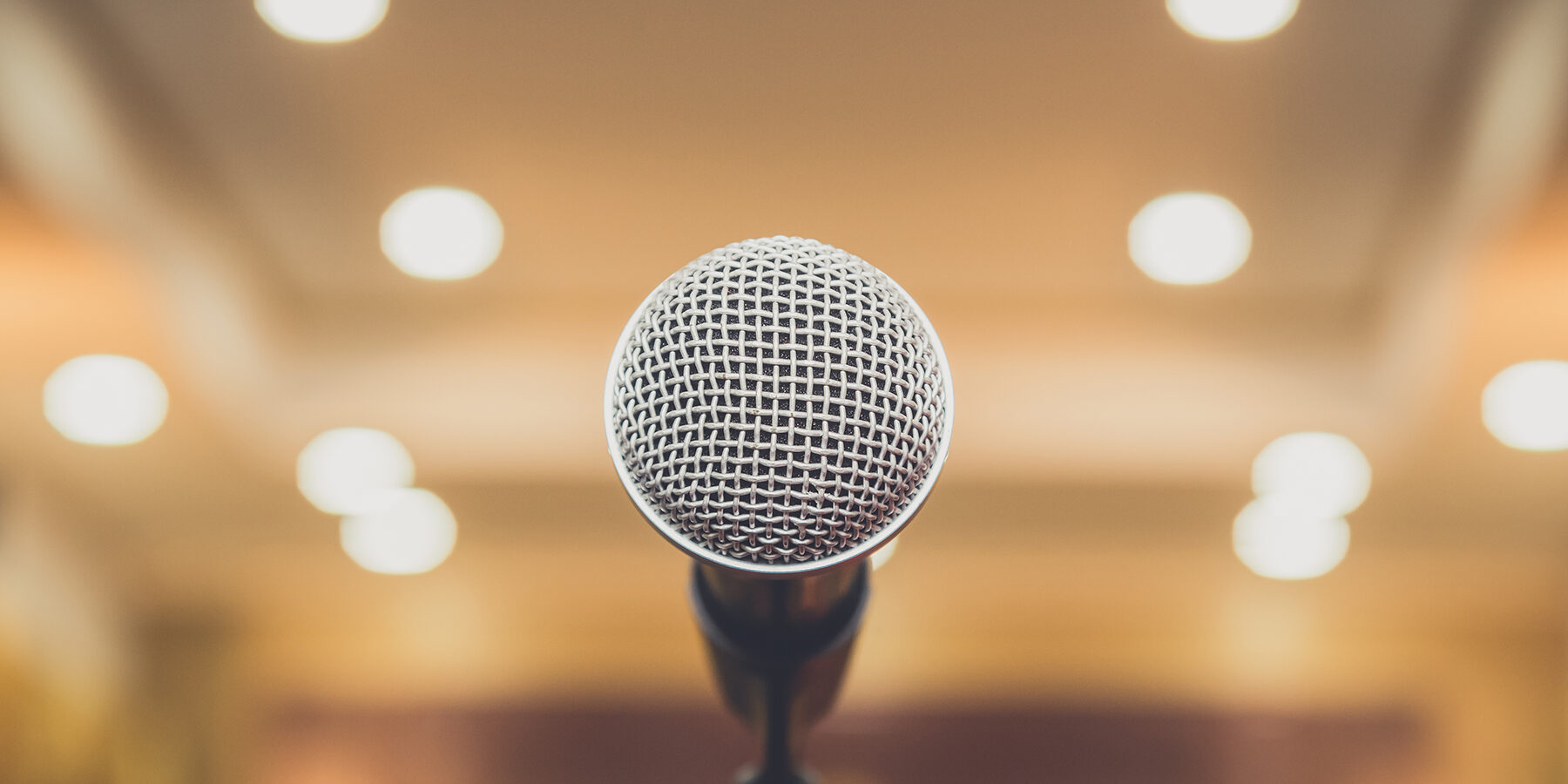 close up image of a microphone in blurred auditorium